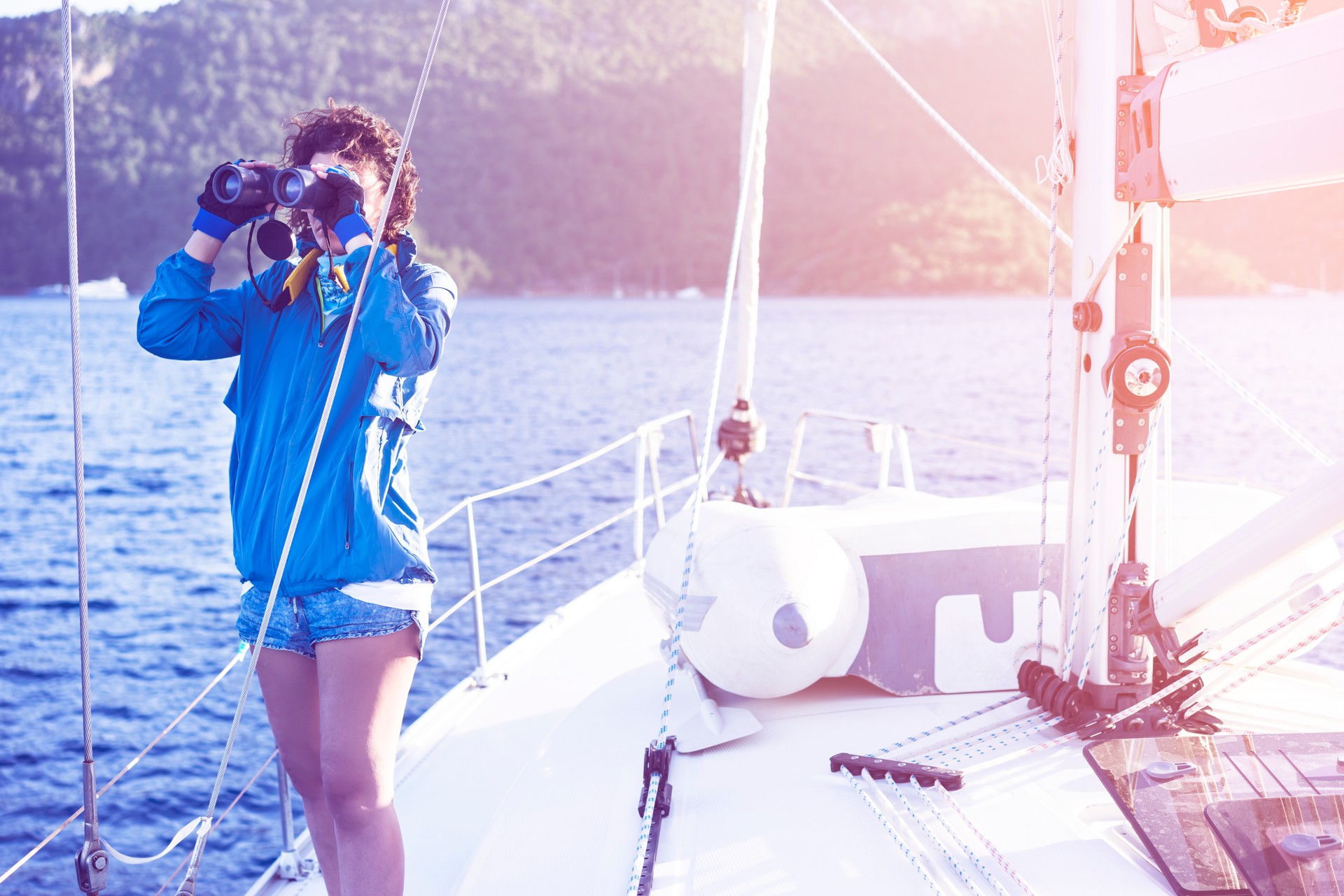 Young woman sailing, looking with binoculars